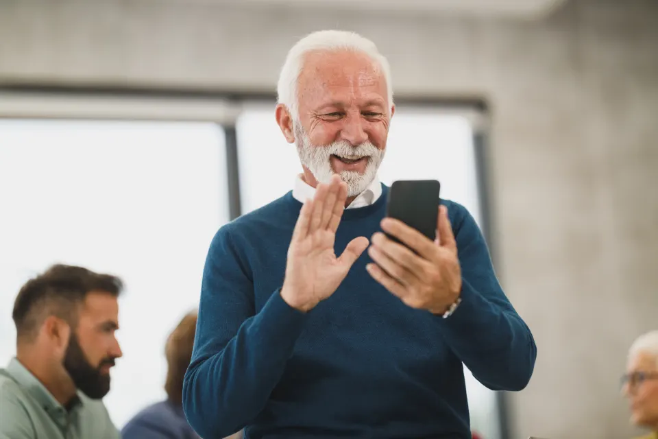 Man waving at his phone during a video call